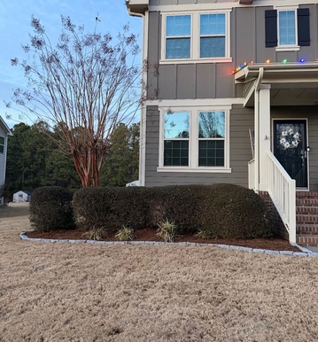 House frontage with trimmed shrubs, mulch and stone bed edging