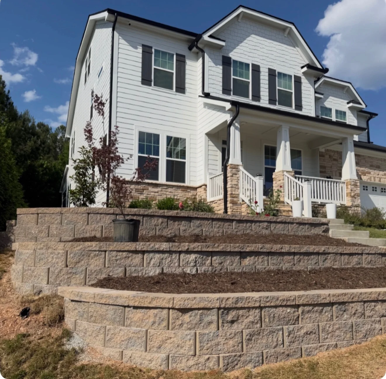 Block retaining walls frame planting beds beside the front steps. YardU project photo.