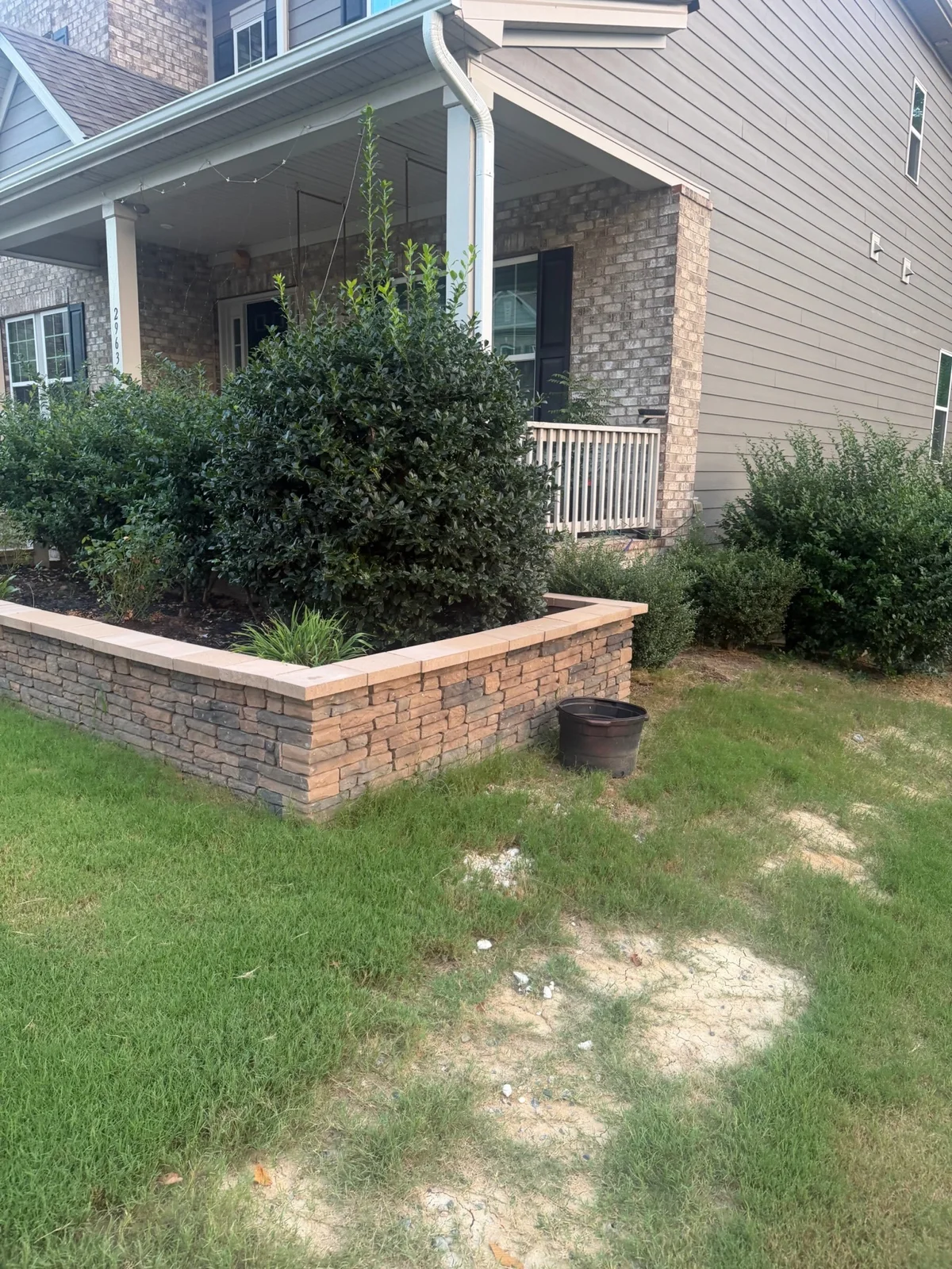 A capped block wall borders a raised garden bed near the front porch. YardU project photo.